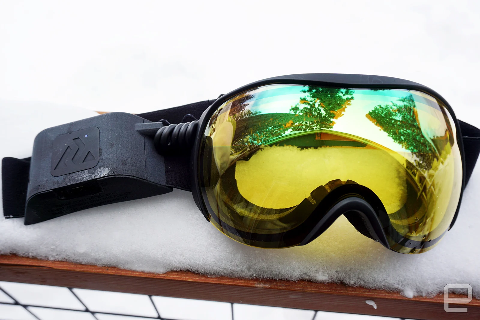 Ski goggles with yellow lenses and a battery pack on the side of the strap.